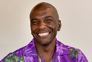 Black man smiling with purple colorful shirt