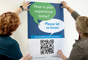 2 people holding up a poster to the wall.