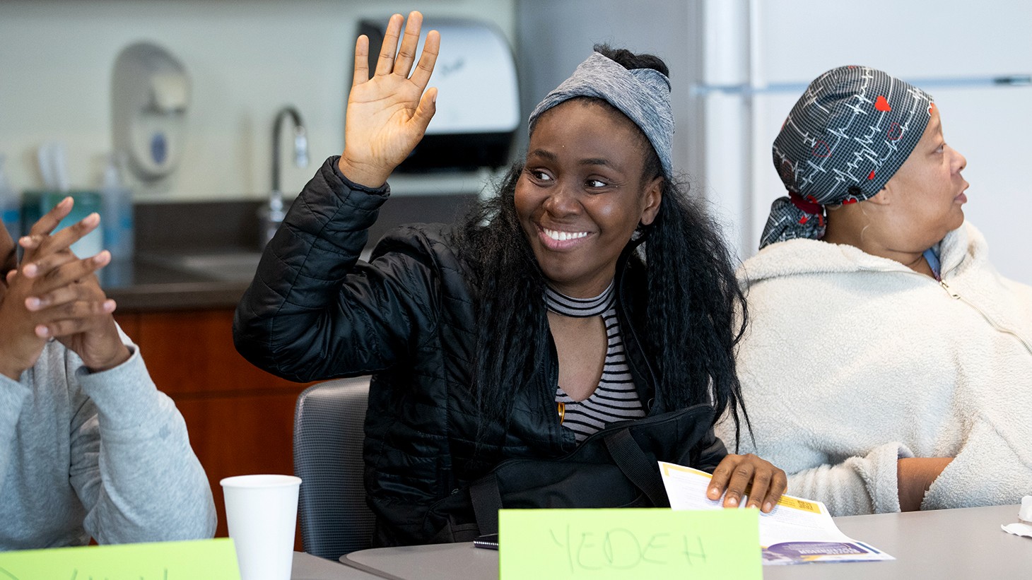 A woman raising her hand and smiling