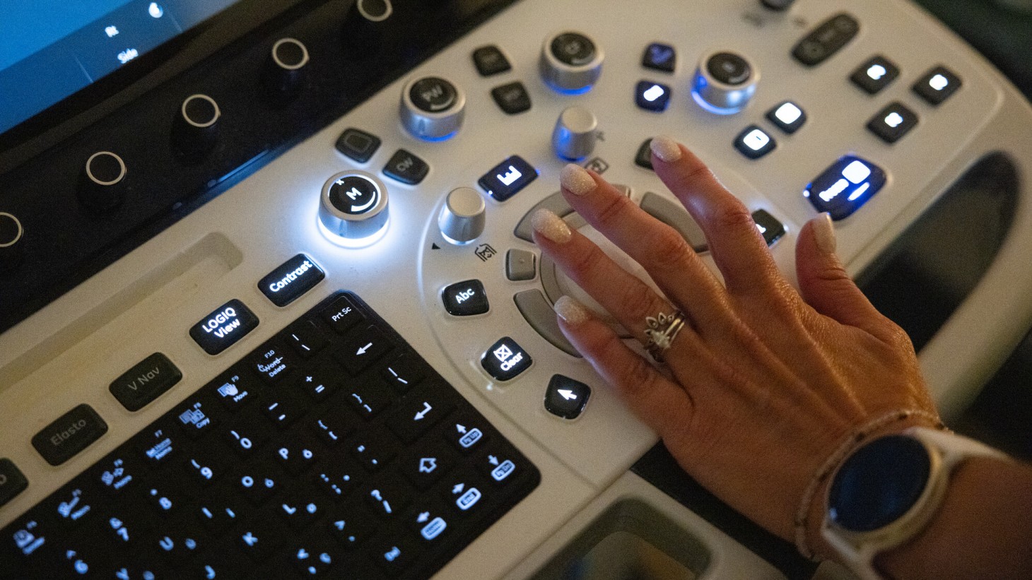 A hand on a radiology machine keyboard