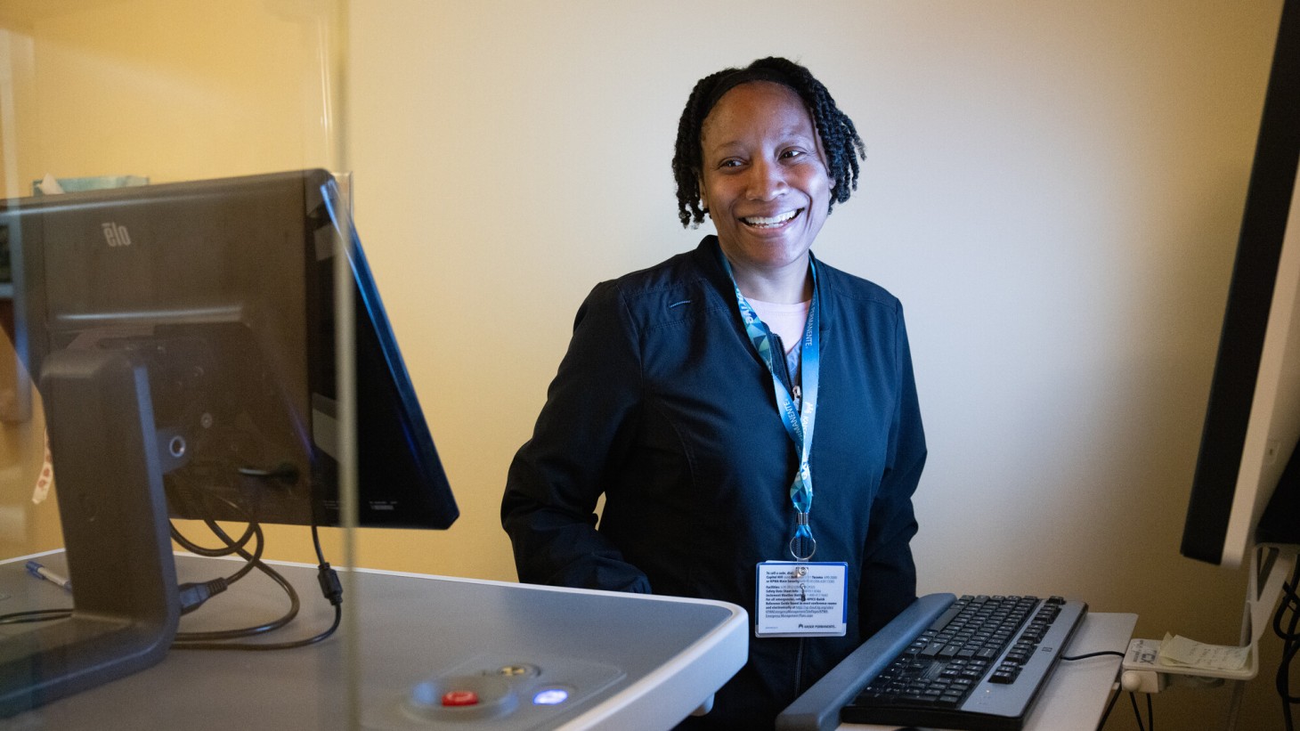 A woman smiling at her work station with monitors