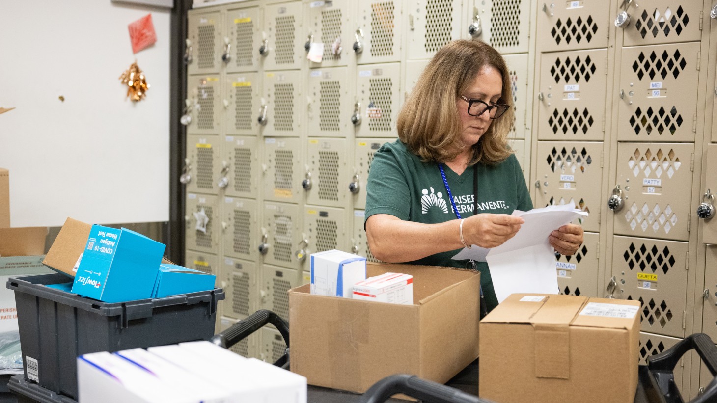 Woman standing among boxes, examining list